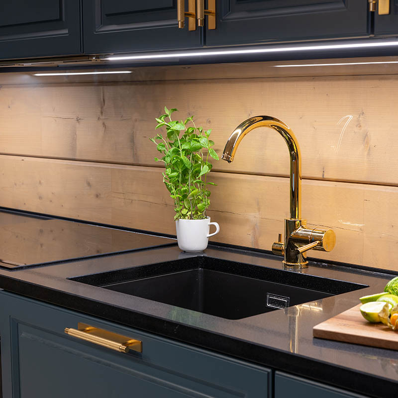 Keittiön taso, jossa komposiittiallas ja kultainen hana.